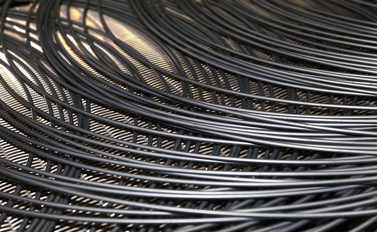 A sharp, close-up photo of a single coil of 5.5mm steel wire rod, showing the smooth metallic surface and the neat winding of the wire.