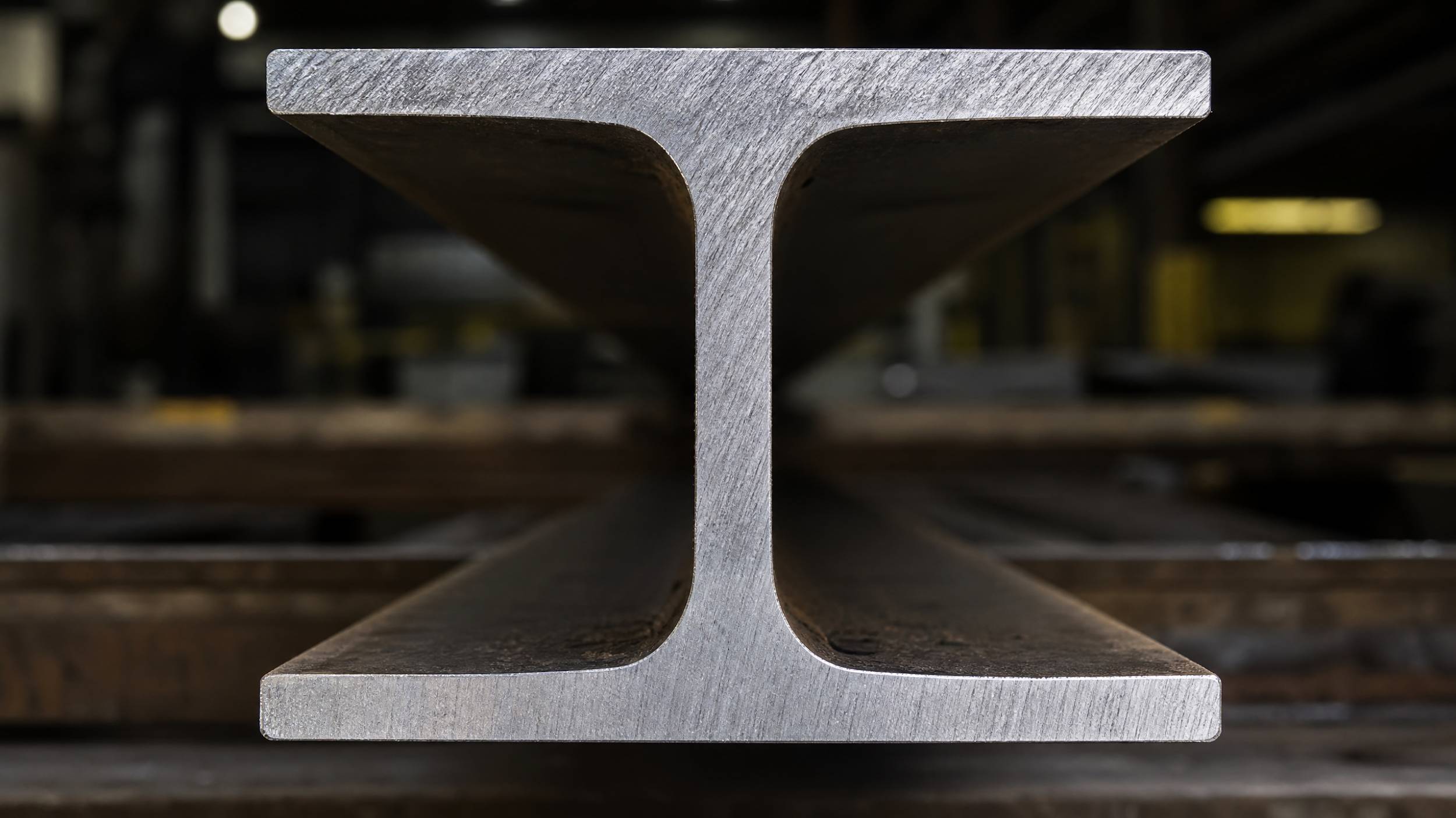  A sharp, close-up photo of the cross-section of an I-beam steel section, showing the distinct I-shape, the web, and the flanges.