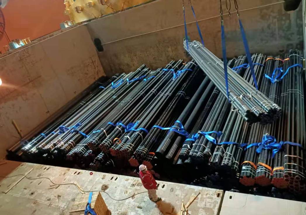 Heavy bundles of steel rebar being loaded with cranes for international shipping
