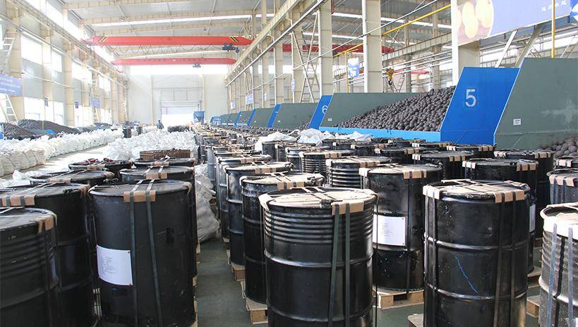 Large steel drums filled with forged grinding balls, neatly arranged on wooden pallets in a clean warehouse, labeled for export.