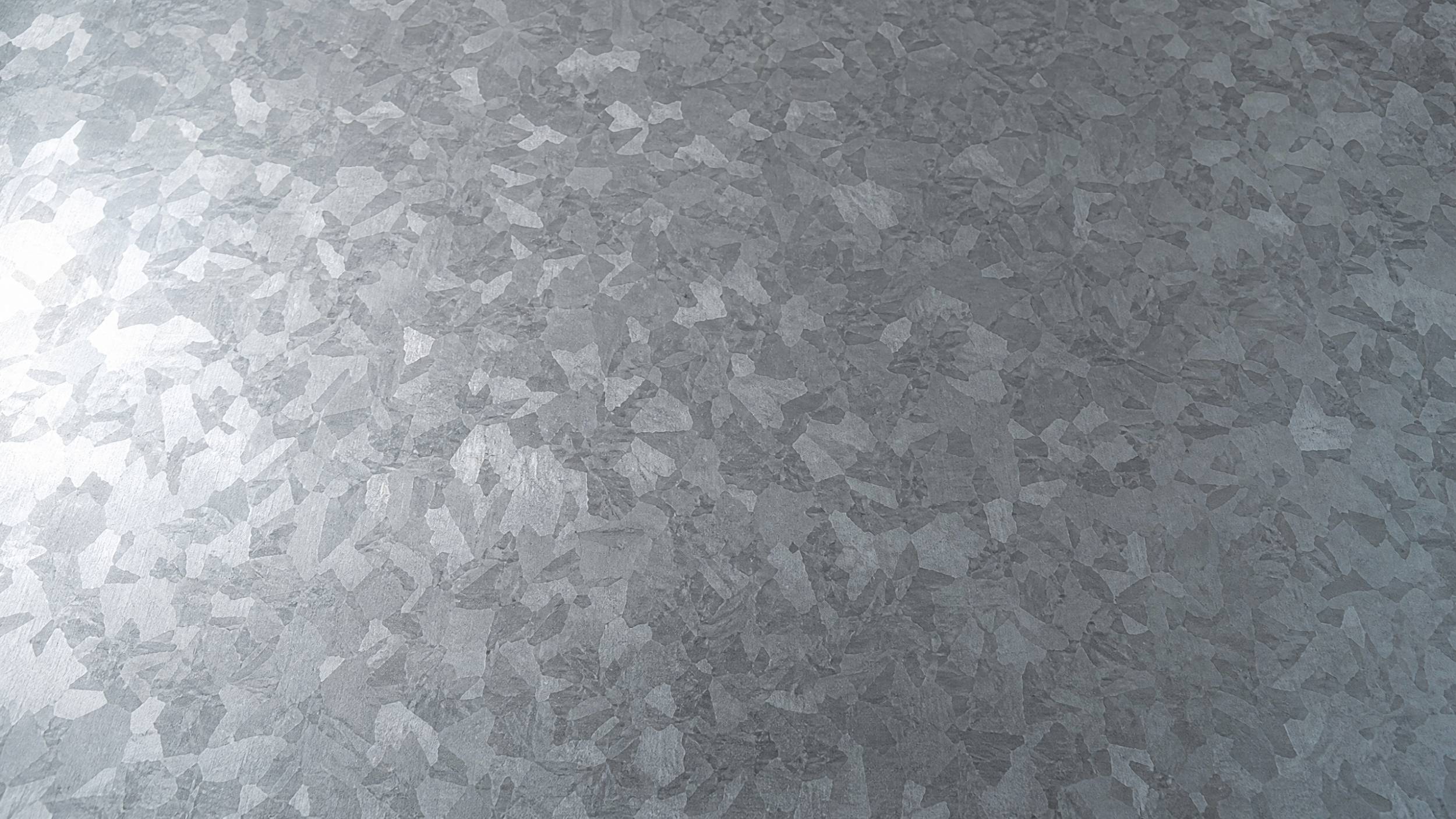 A sharp, close-up photo of the surface of a galvanized steel sheet, showing the distinct "spangle" pattern of the zinc coating.