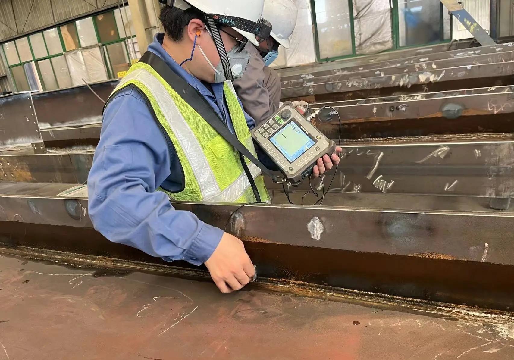 A professional quality inspector reviewing an SII Compliance 2026 document while inspecting steel beams in an industrial setting.