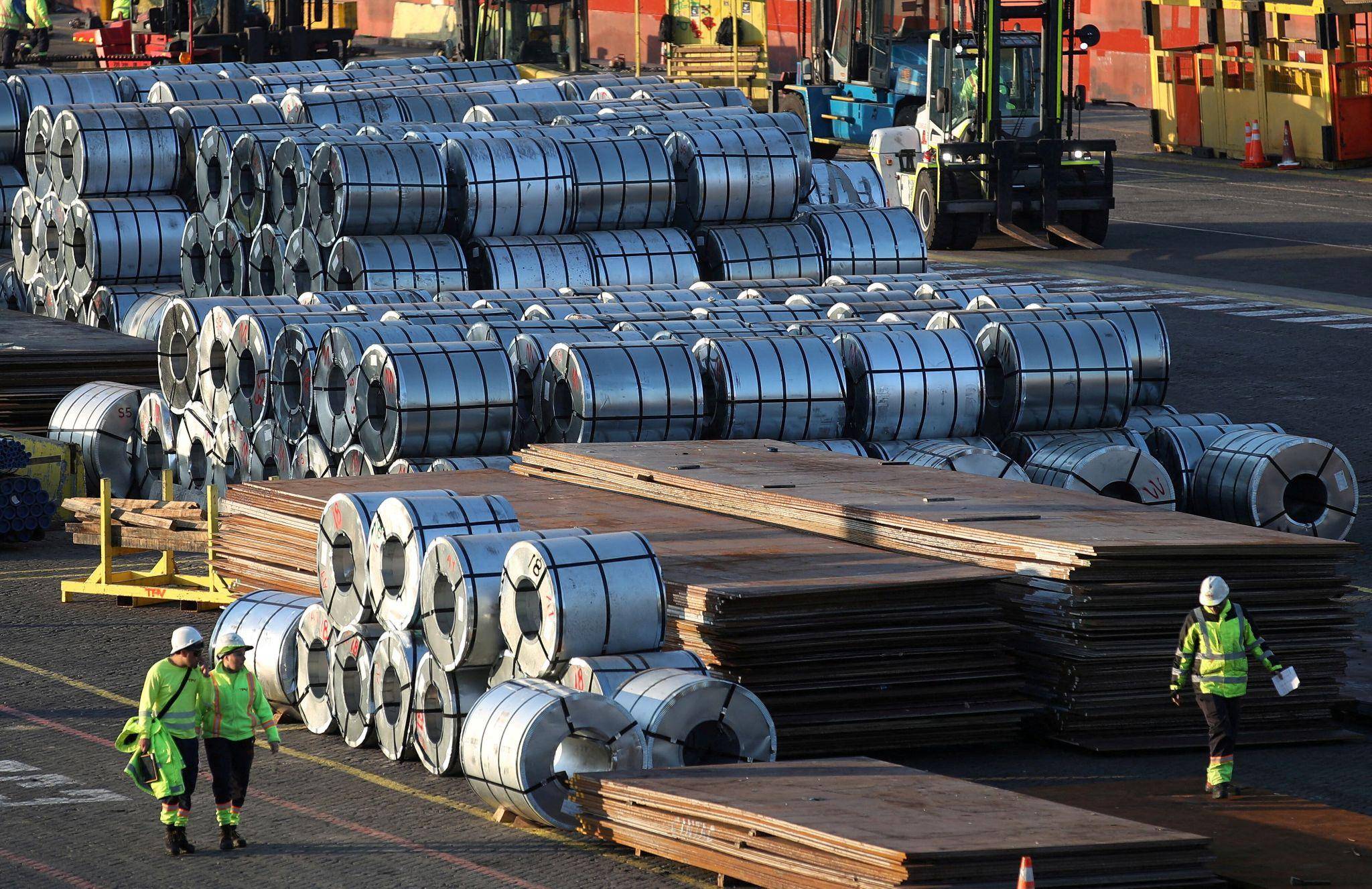 Large steel coils stored in a modern factory with worker overseeing operations