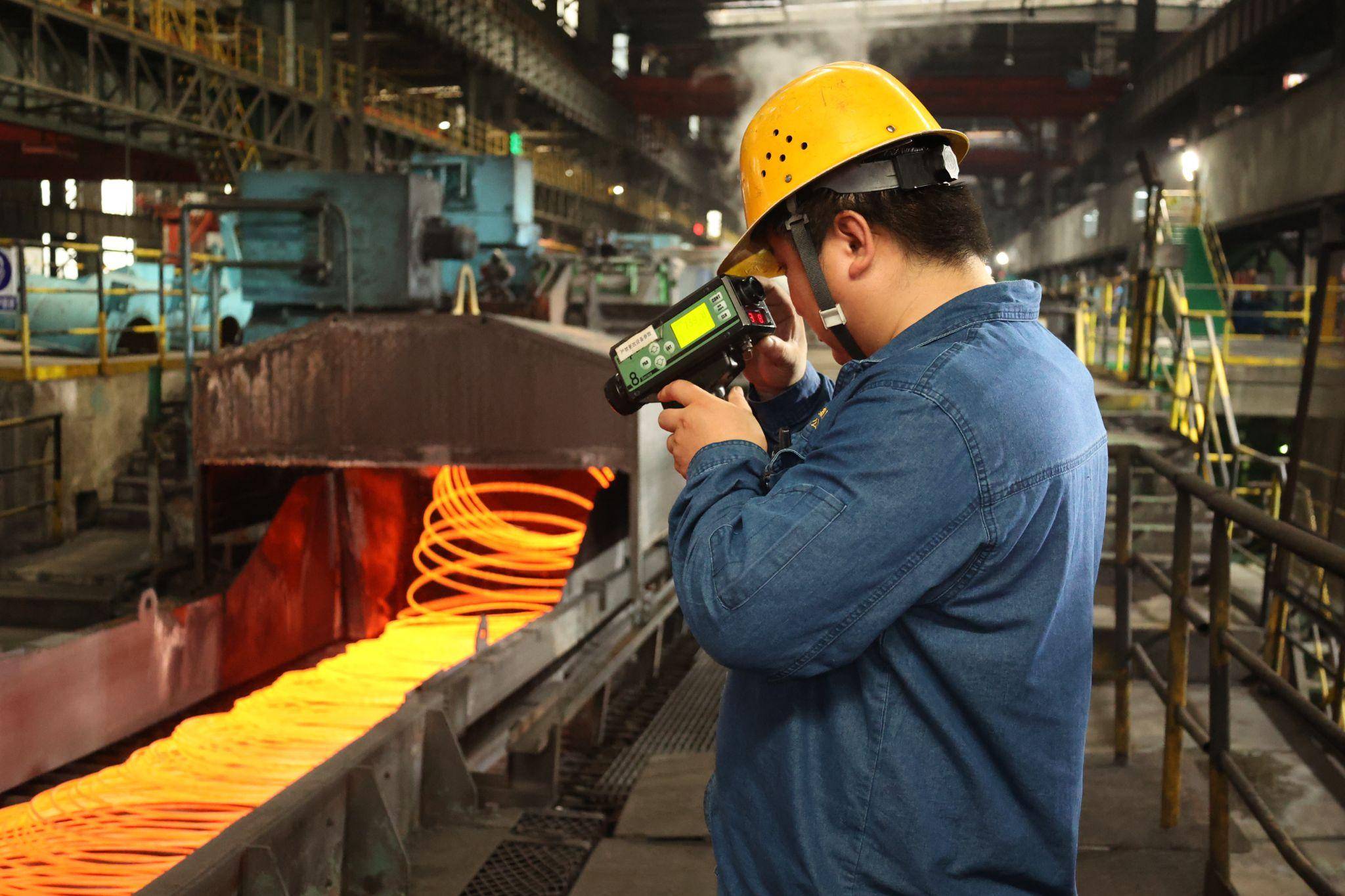 Technician using infrared thermometer to monitor molten steel in Chinese mill