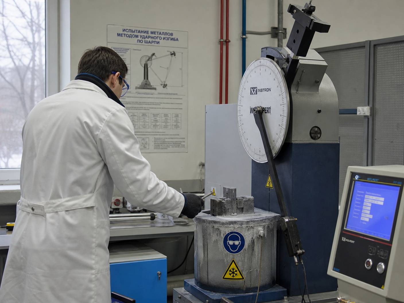Technician performing Charpy impact test on steel sample in laboratory