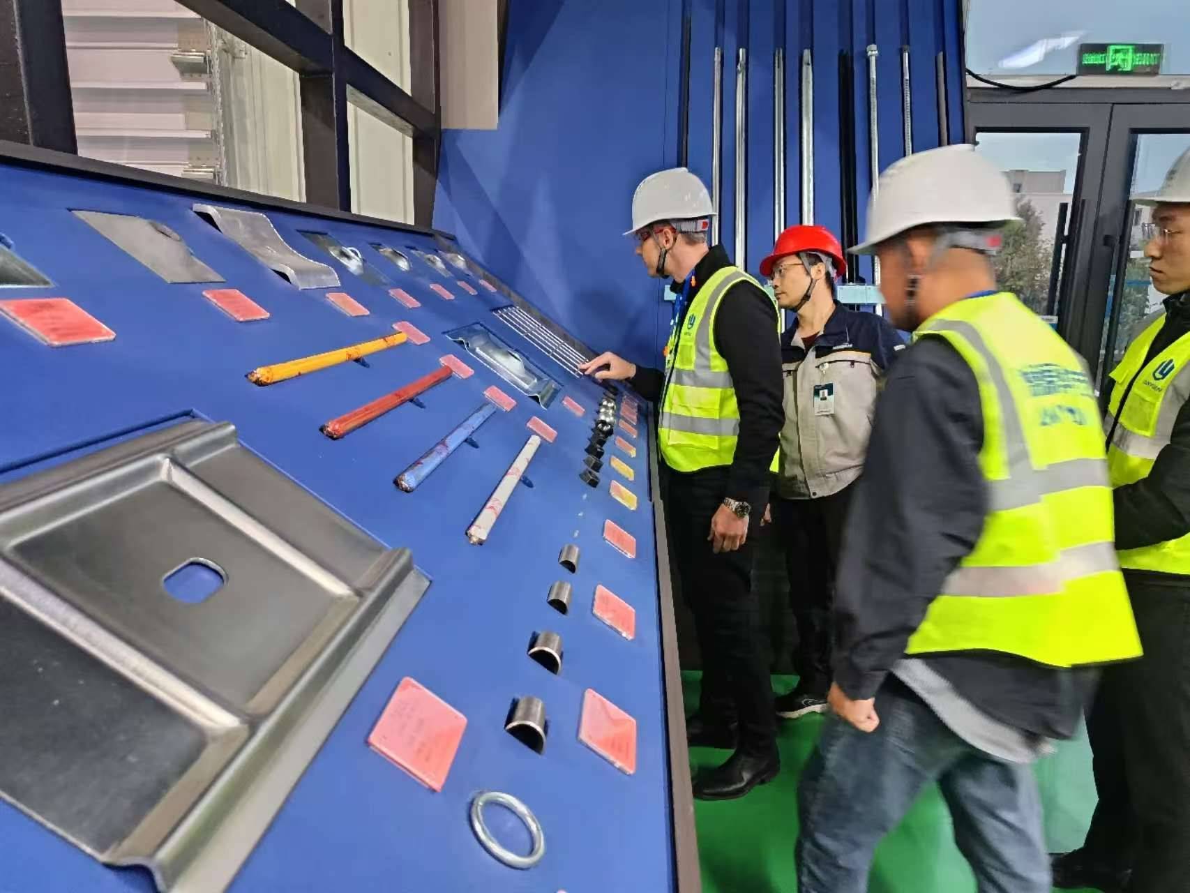 Asian Chinese engineers, a man and a woman, in hard hats and safety vests, pointing at a modern building structure, discussing material selection.