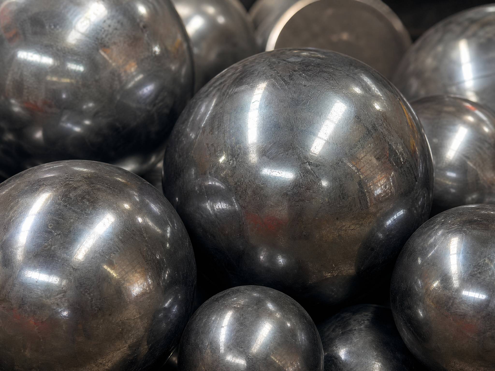 Extreme close-up of polished forged steel grinding balls of different diameters, showcasing their smooth, metallic surfaces.