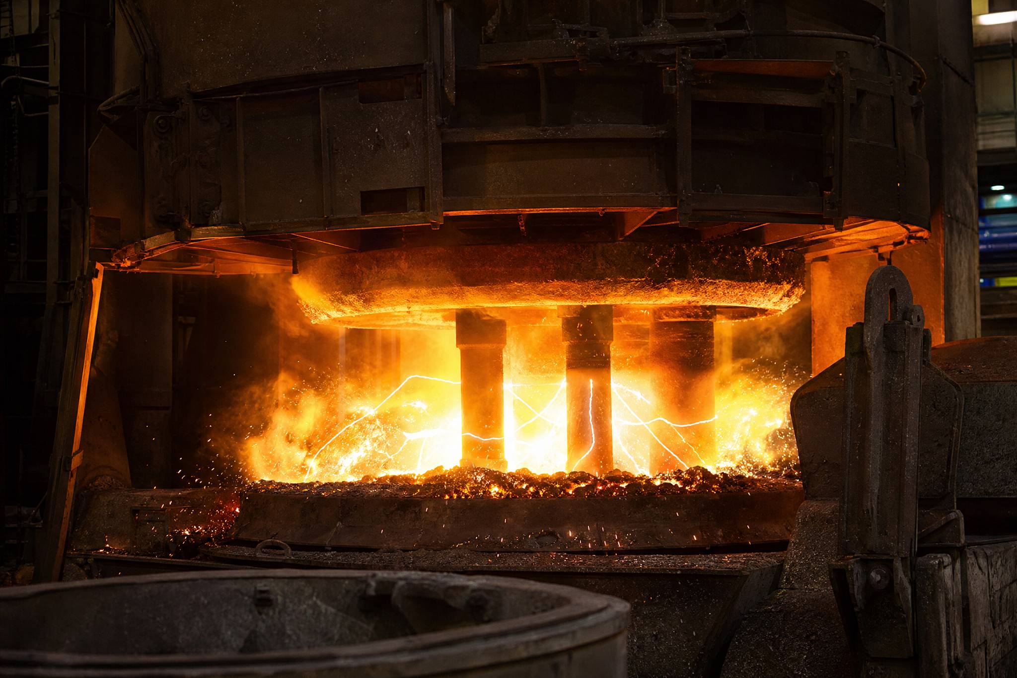 Close-up of an Electric Arc Furnace (EAF) with bright electric arcs melting scrap steel, showcasing the high-temperature steelmaking process.