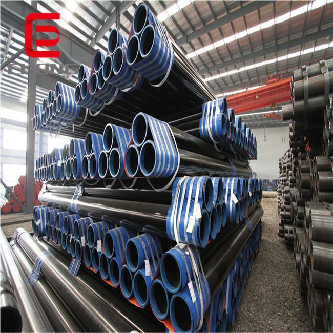 Stacks of black-coated seamless steel pipes in a large, clean warehouse.